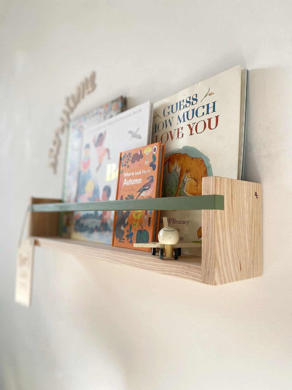 Wooden shelf with children's books on a white wall