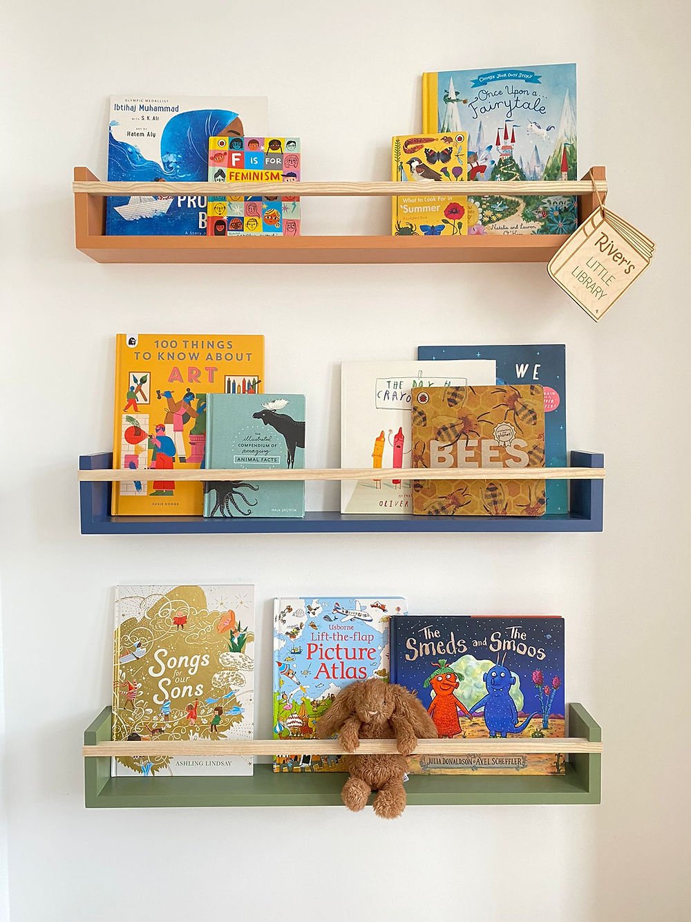 Children's books on wooden shelves against a white wall