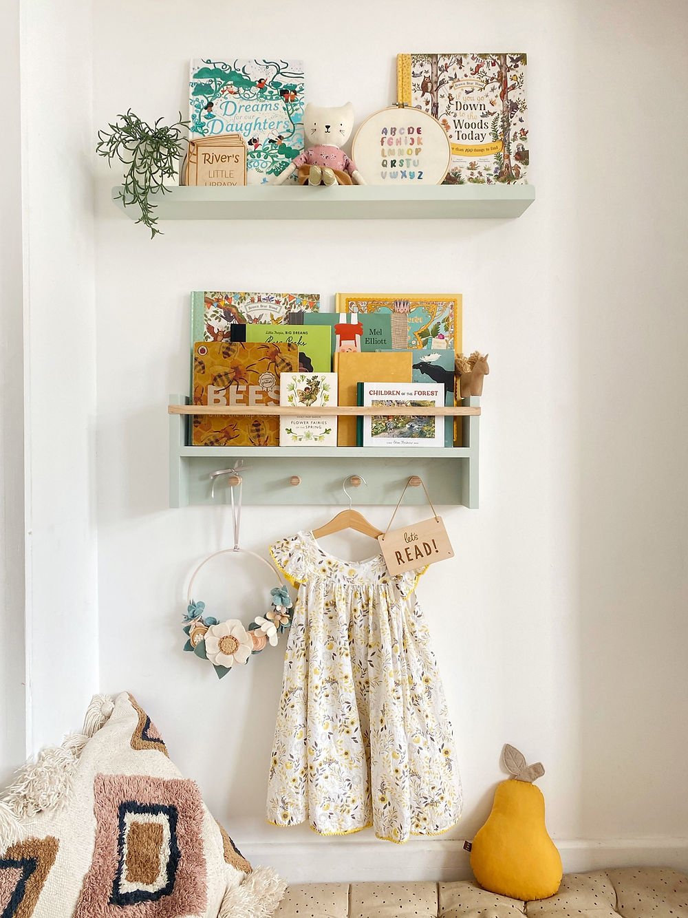 Children's room with shelves displaying books, a dress, and decorative items.