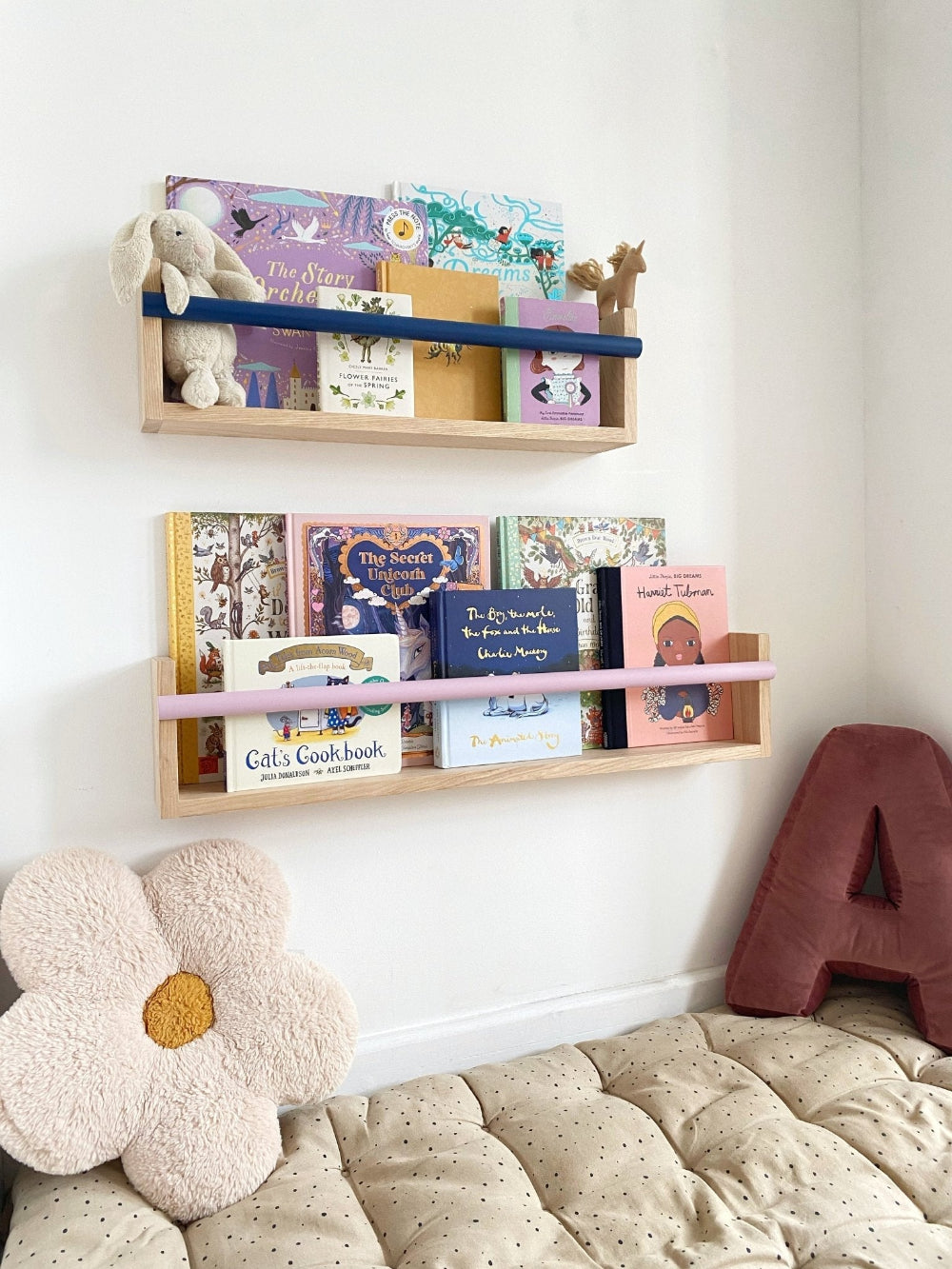 Children's bookshelves with books and toys against a white wall.