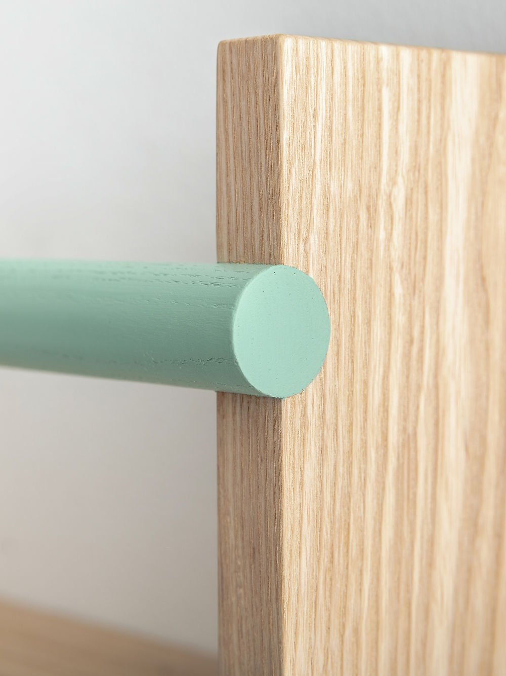 Close-up of a wooden surface with a green cylindrical object on a light gray background