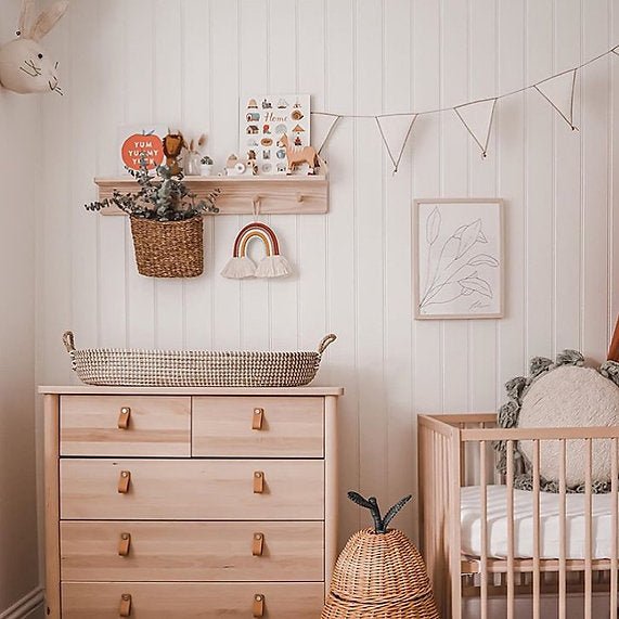 Nursery room with wooden dresser, crib, and decorative elements.