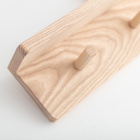 Wooden peg shelf with a small pegs on a white background