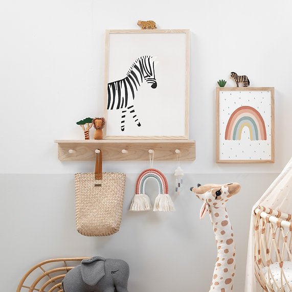 Nursery wall decor with framed zebra print, rainbow, and children's toys.