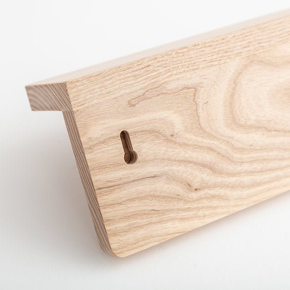 Close-up of a wooden peg shelf board with a keyhole on a white background
