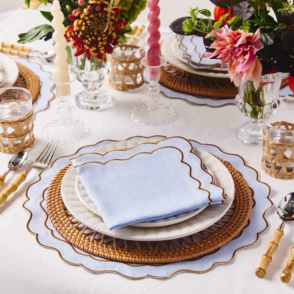 Elegant table setting with floral centrepieces, gold-rimmed plates, and wicker chargers.