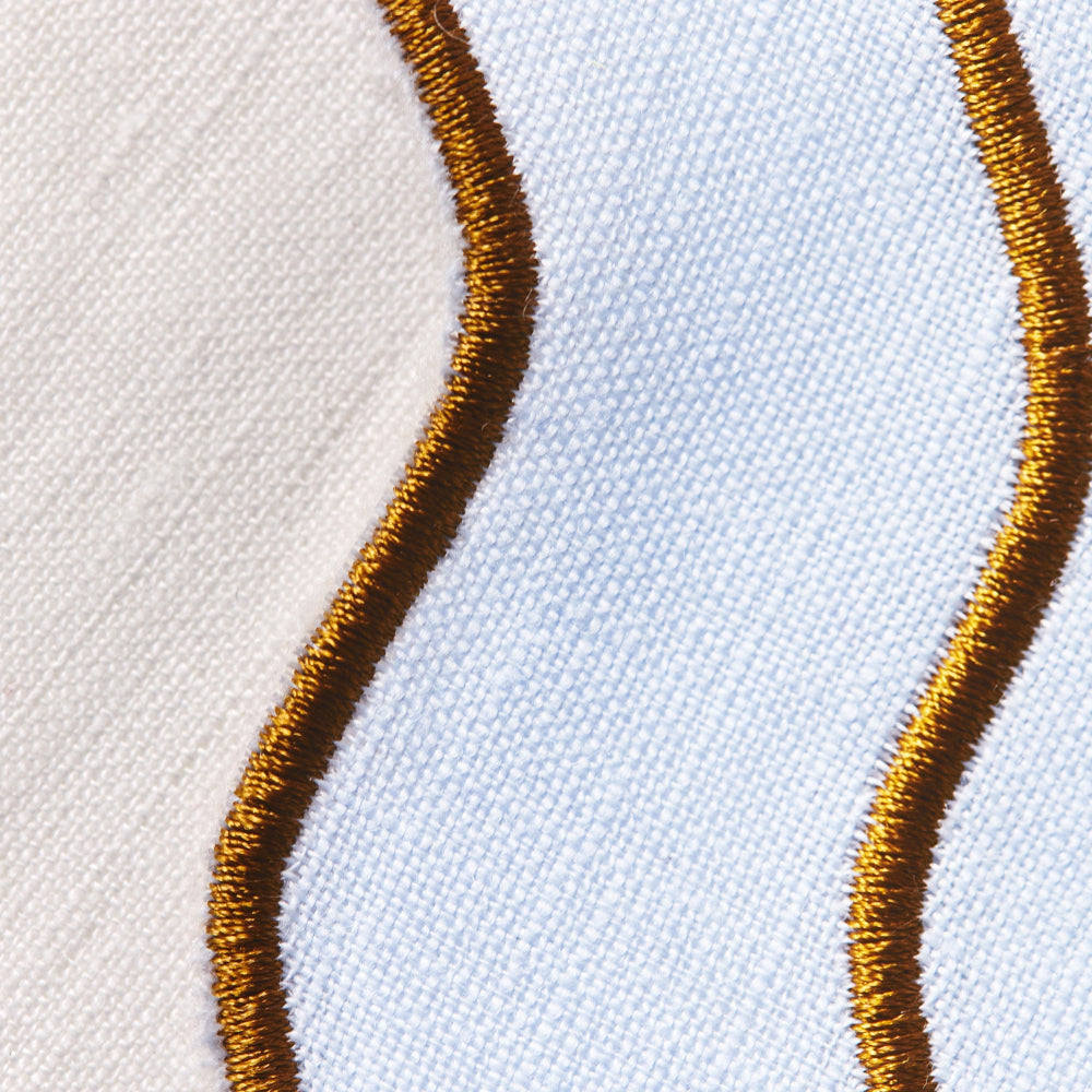 Close-up of gold embroidery on a baby blue scalloped edge placemat