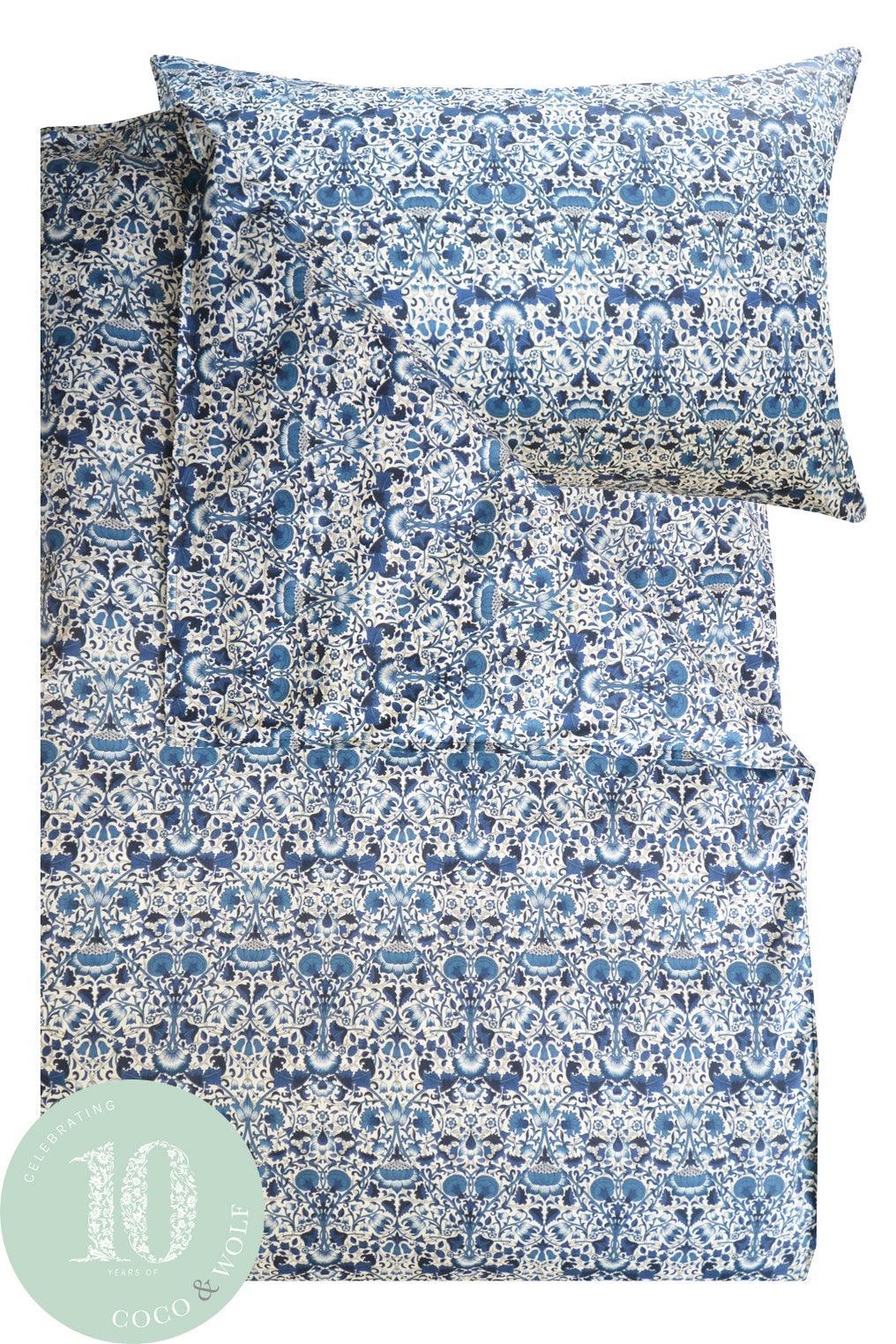Blue and white Liberty patterned bedding set with a pillow and duvet cover on a white background.