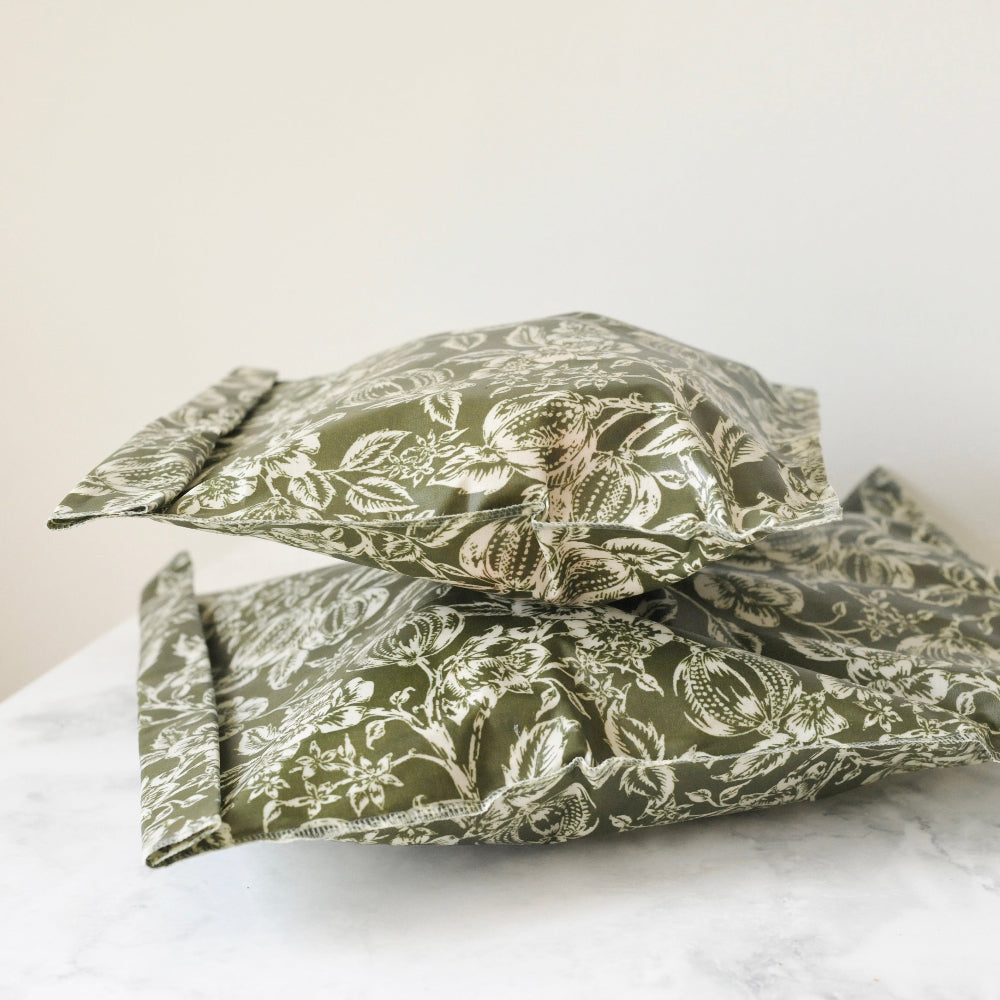 Two green beeswax food storage bags on a white surface