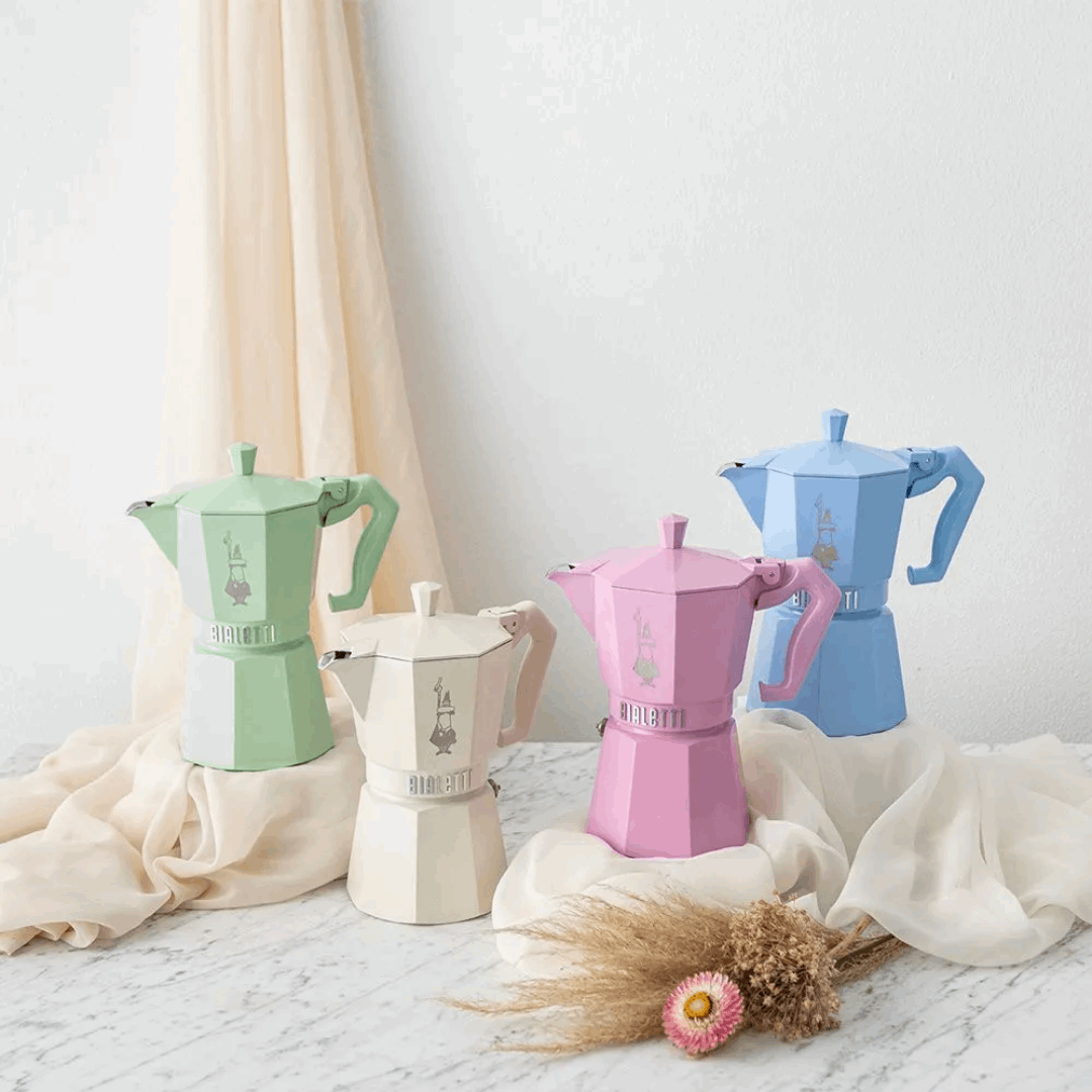 Four colourful Bialetti coffee makers on a light surface with a neutral background