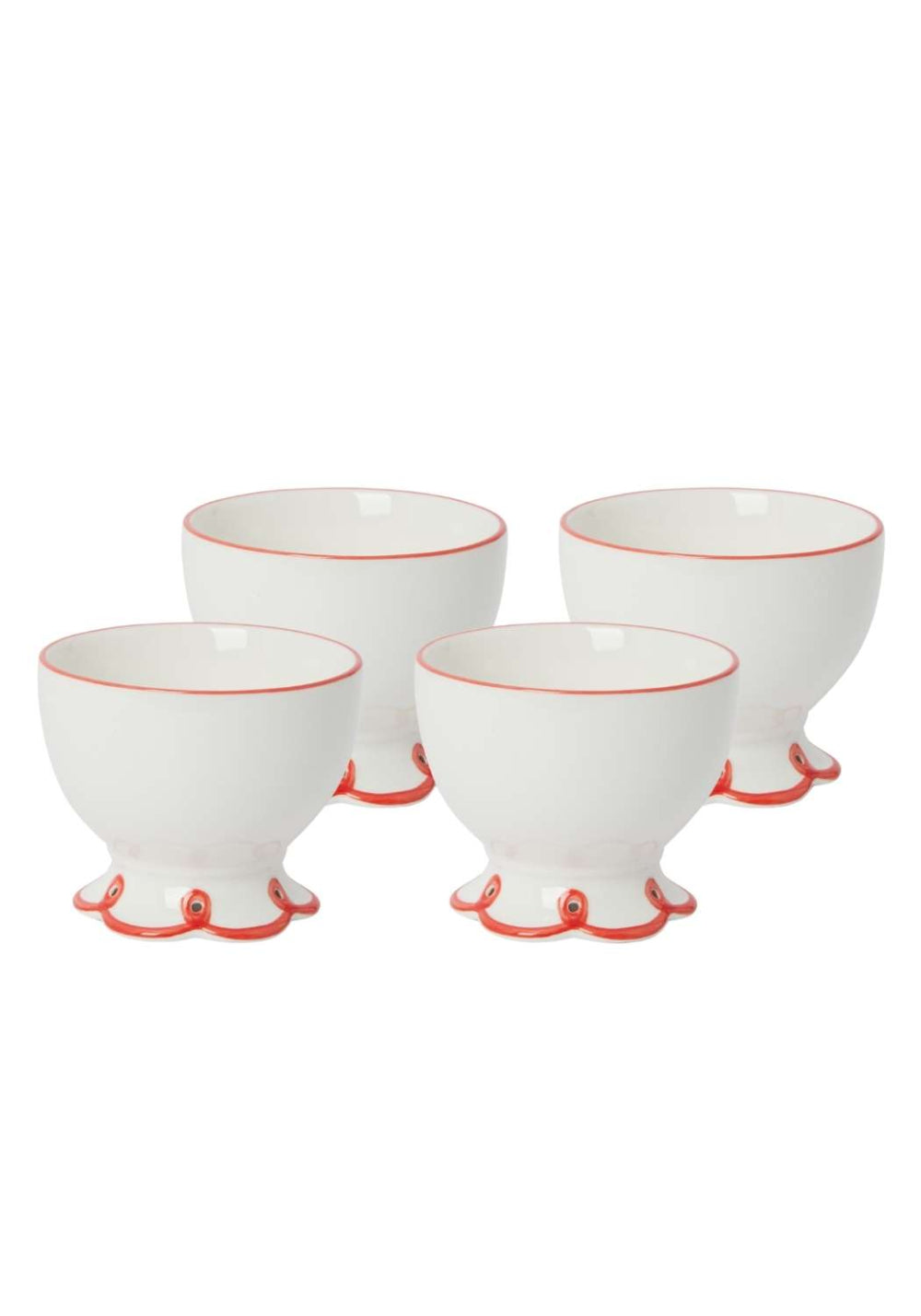 Set of four white ceramic bowls with red scalloped bottoms on a white background