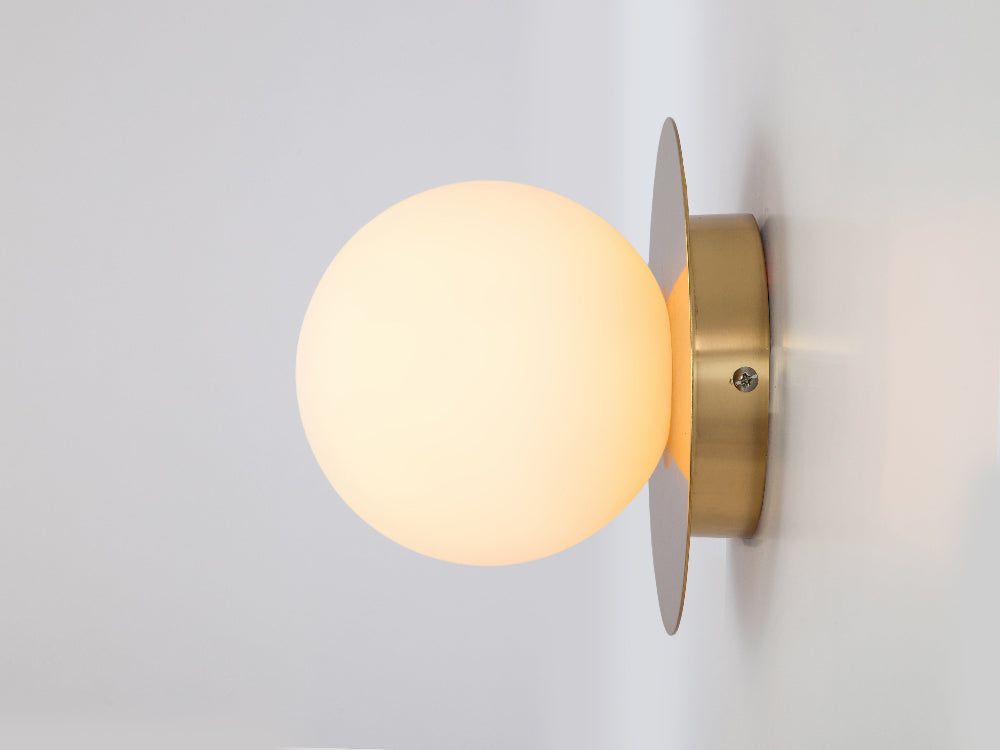 Brass opal wall light styled in a bathroom
