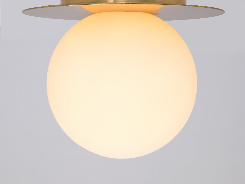 Close-up of polished brass fitting with opal glass shade