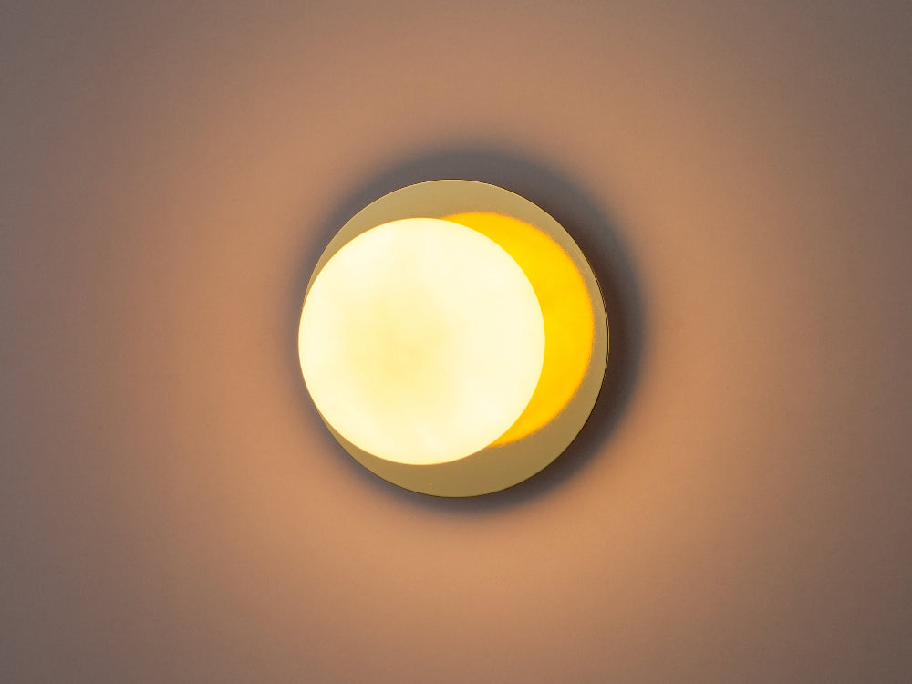 Brass opal wall light positioned beside a bathroom mirror