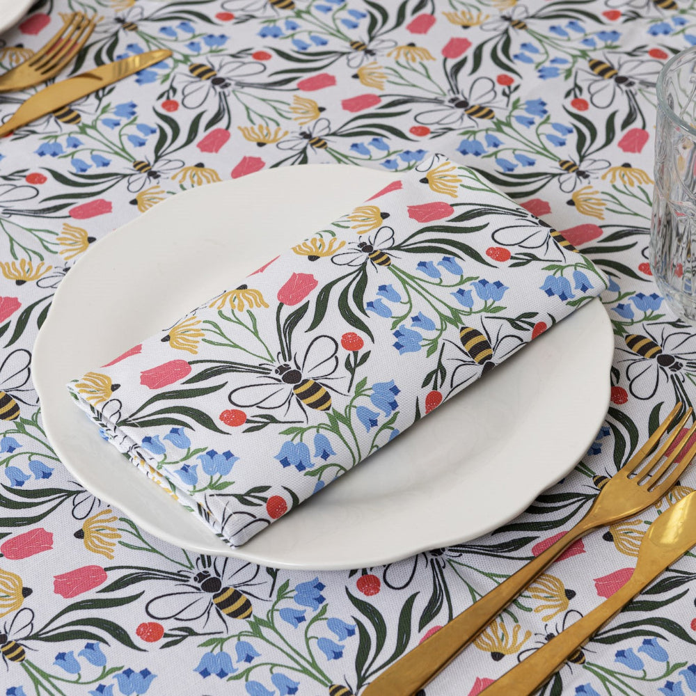 Table setting with floral-patterned napkin, plate, and cutlery on a matching tablecloth.