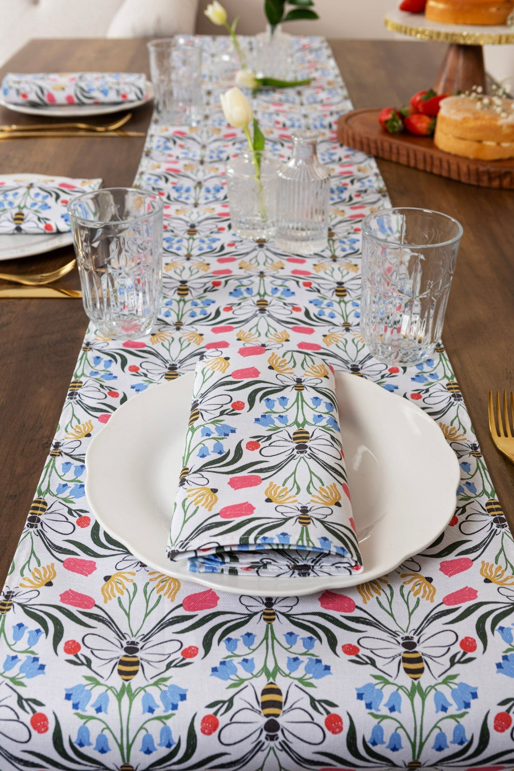 Dining table set with a floral tablecloth, plates, glasses, and cutlery.