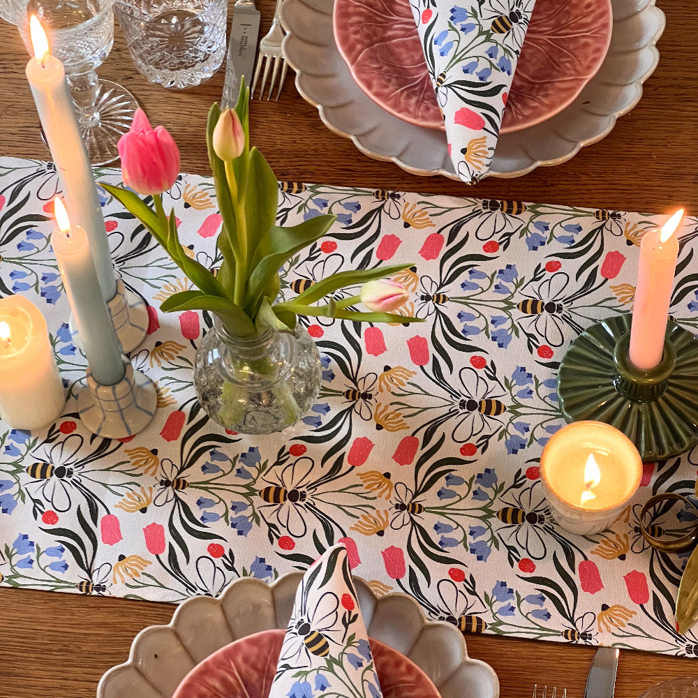 Decorative table setting with candles, flowers, and a patterned tablecloth.
