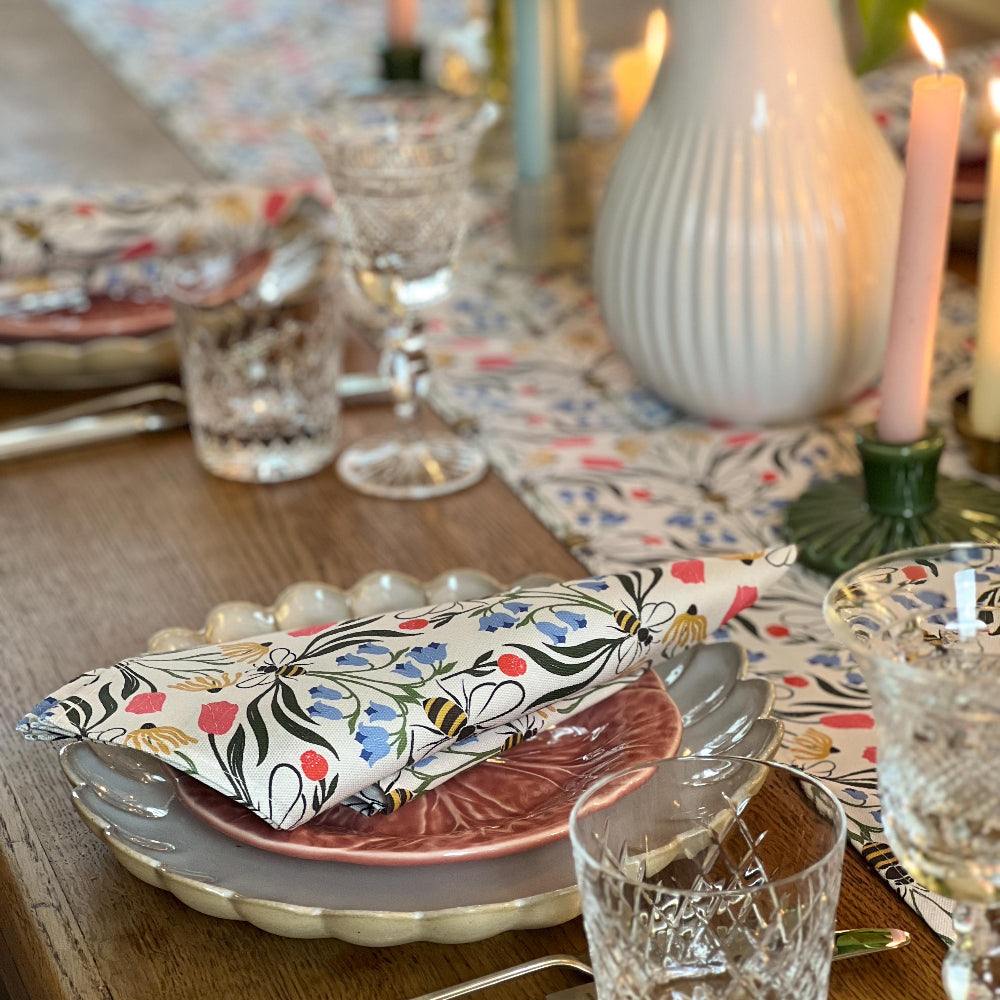 Decorative table setting with floral-patterned napkins and cutlery on a wooden table.