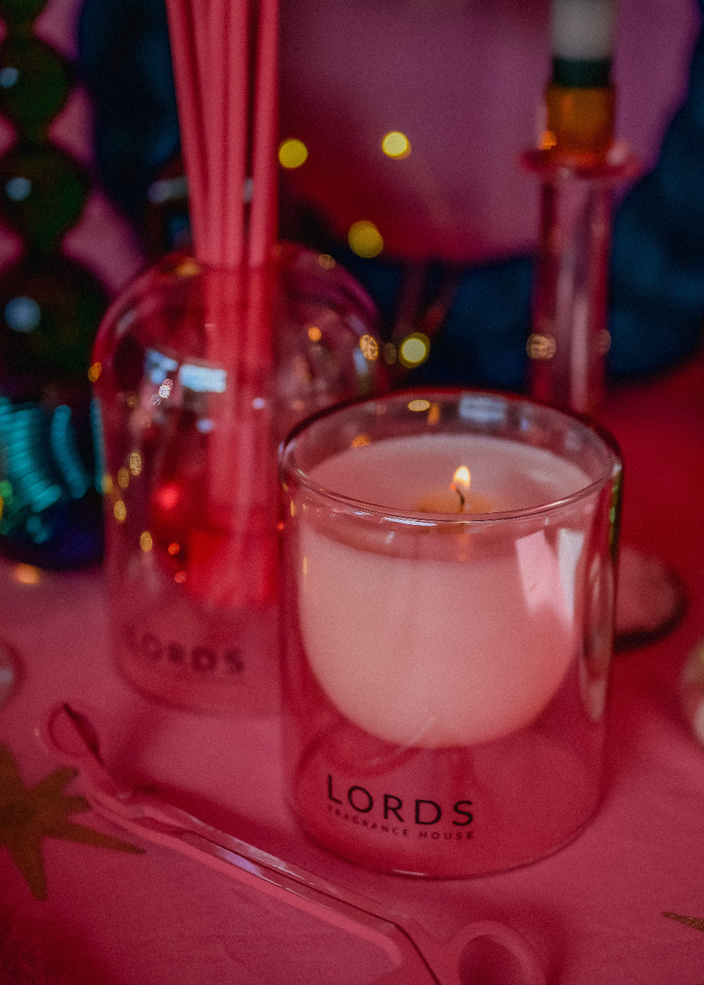 Lords candle on a pink surface with colorful lights in the background