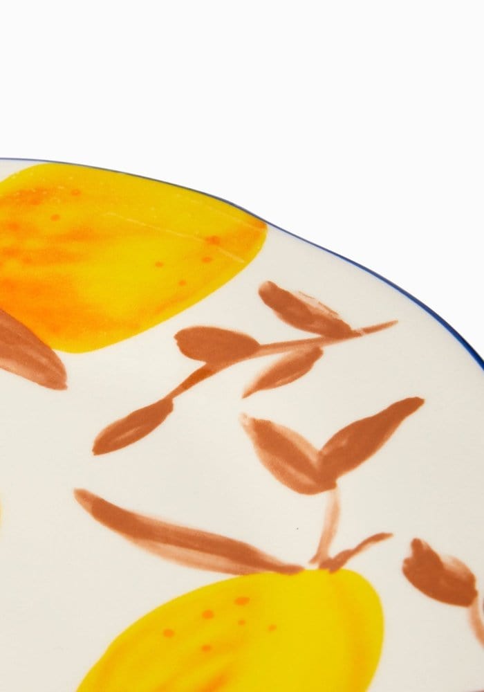 Decorative plate with yellow fruit and brown leaves on a white background