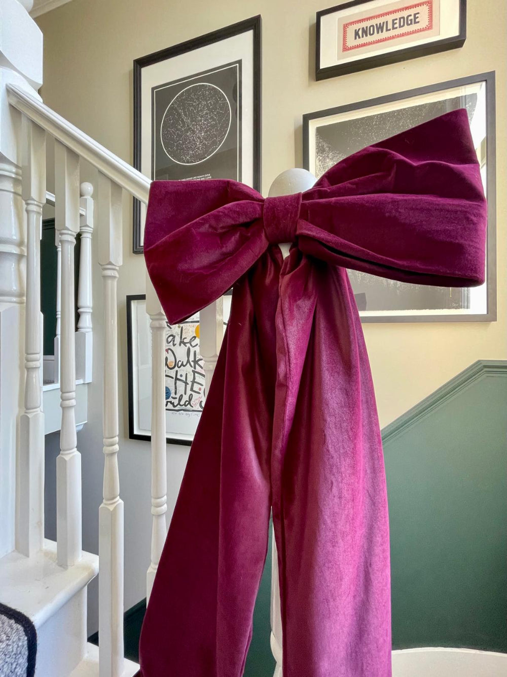 Burgundy velvet Christmas bow used as a statement staircase decoration