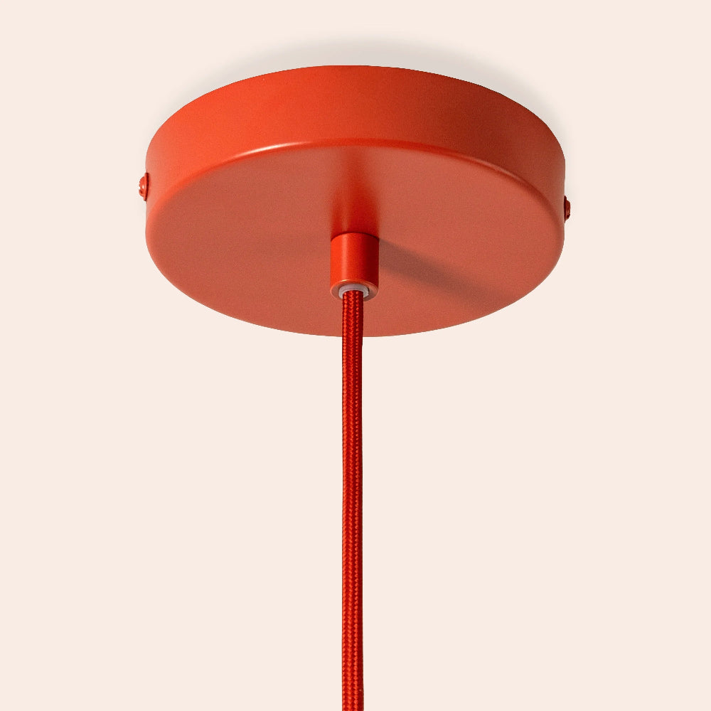 Red ceiling light fixture with a cord on a beige background