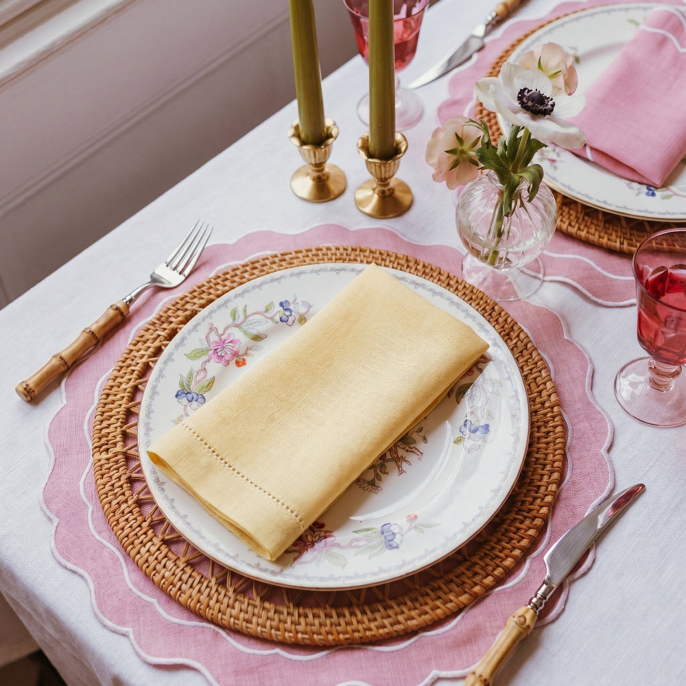 Elegant table setting with a rolled-up buttermilk napkin on a decorative plate, surrounded by glasses and cutlery.