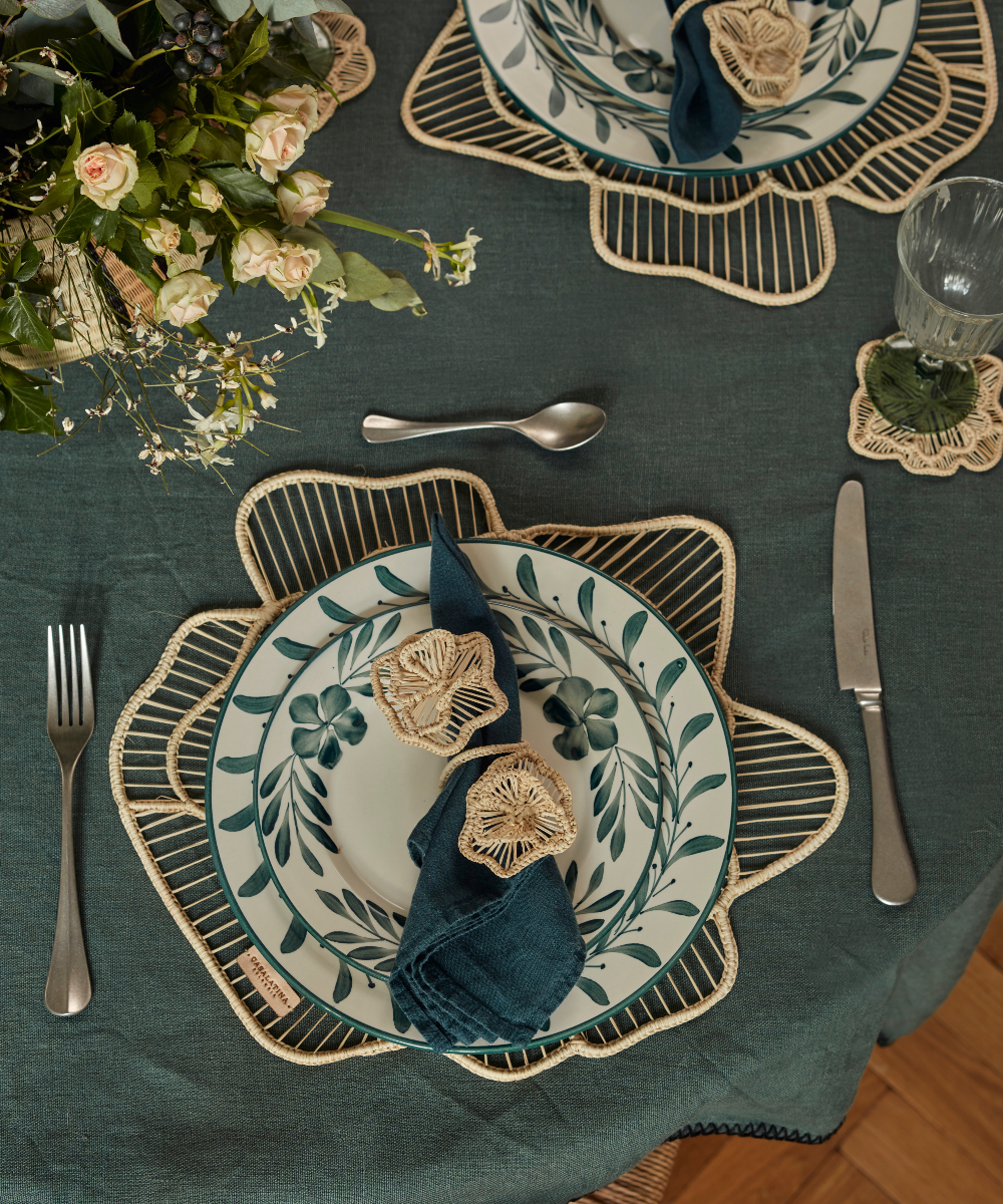 Decorative table setting with floral plates, napkins, and cutlery on a green tablecloth.