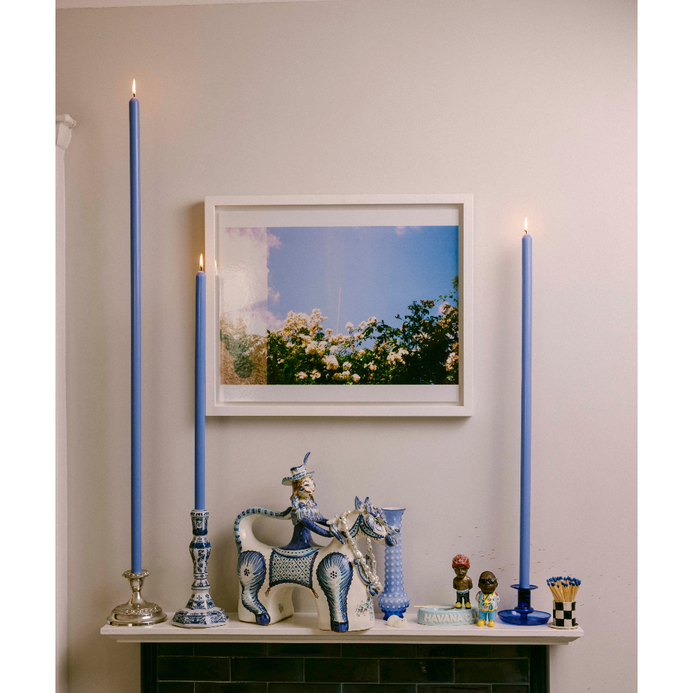 Decorative mantel with blue candles, a framed picture, and various small figurines.