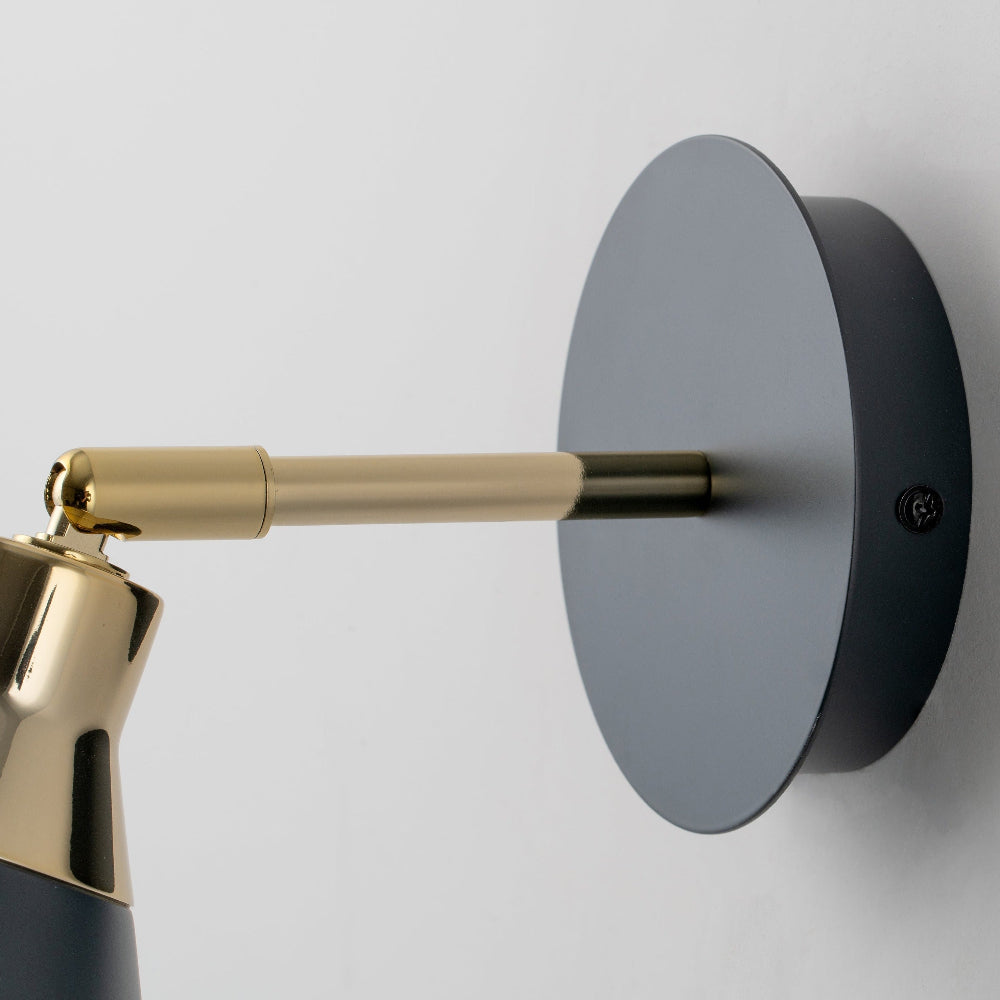 Wall-mounted lamp with gold arm and black base on a light gray background