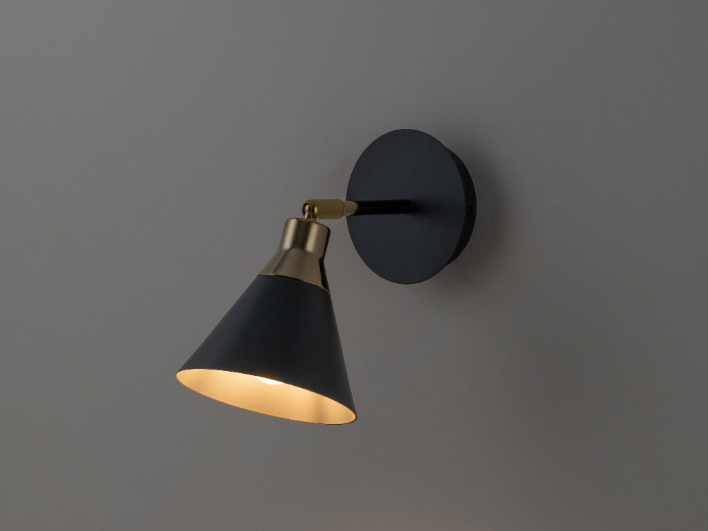 Wall-mounted lamp with black shade and gold interior on a gray background