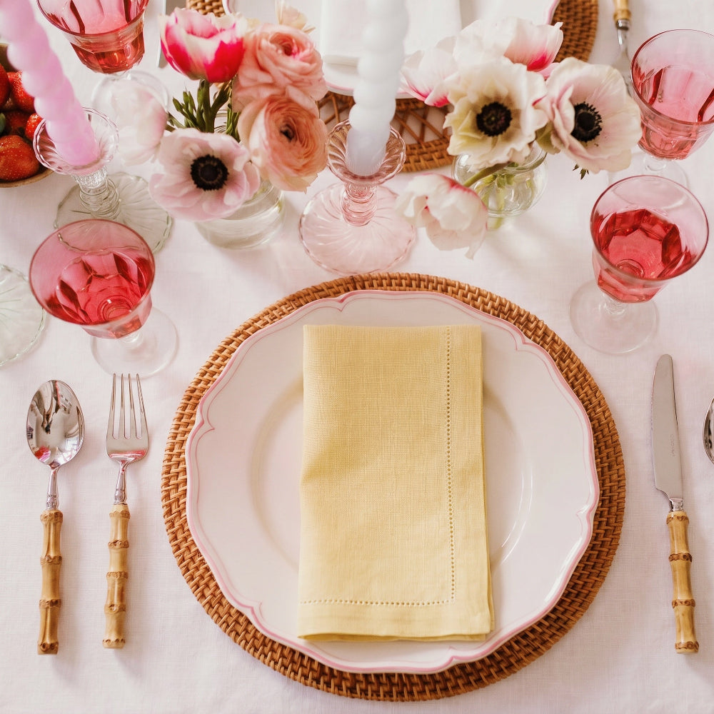 Elegant table setting with pink glasses, floral centerpieces, and gold napkins.