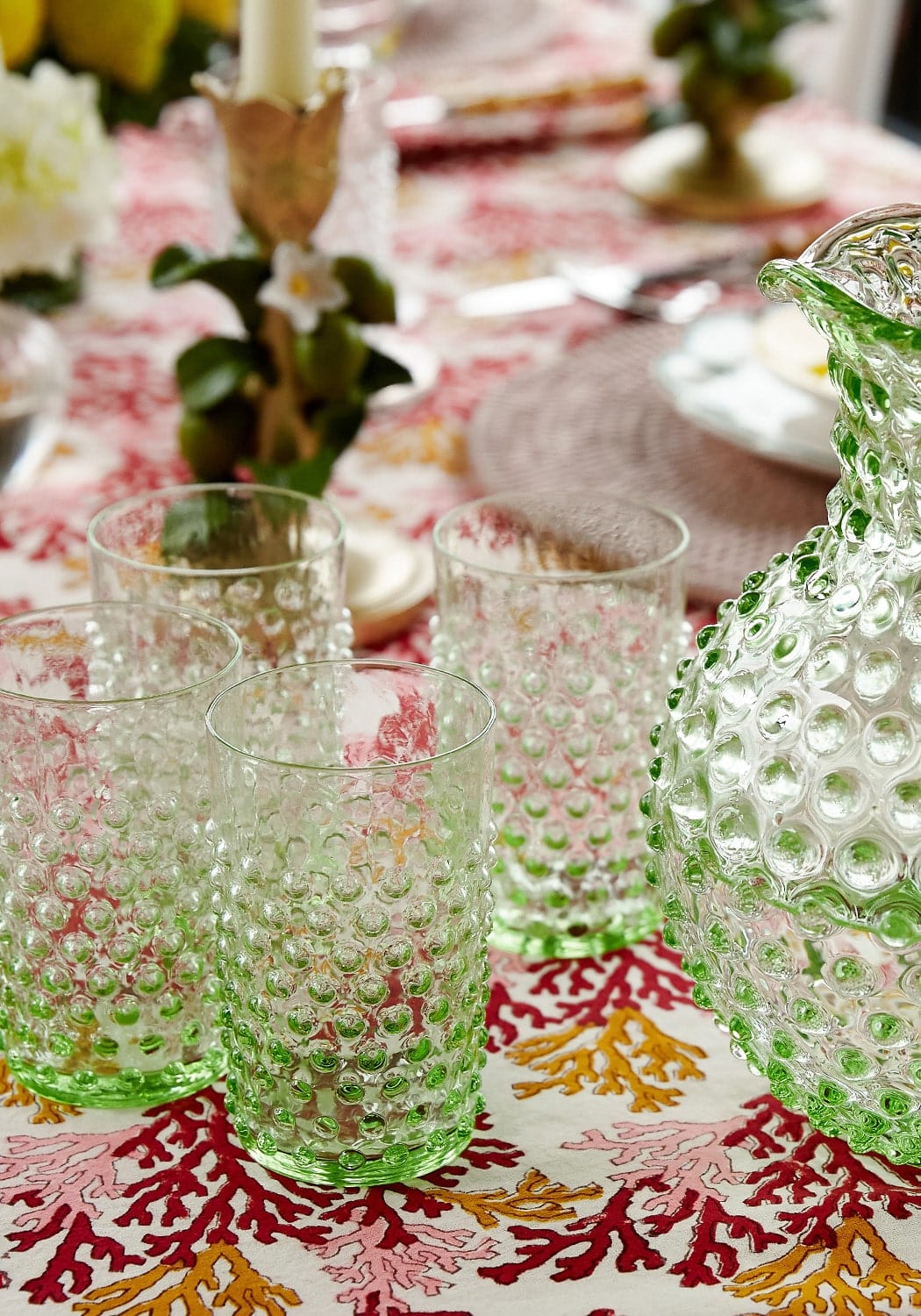 Four green bobbled glass tumblers styled next to matching jug