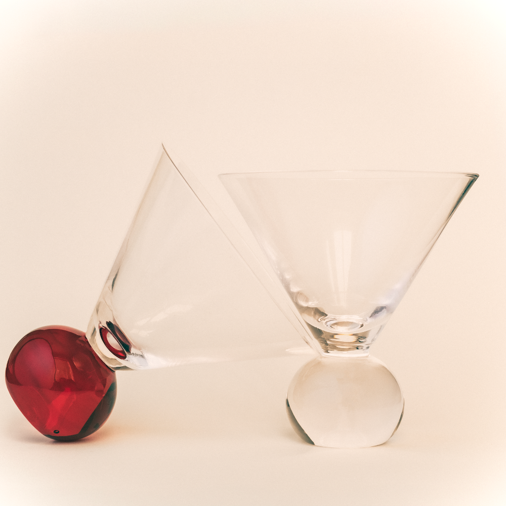 Two clear glass cocktail glasses Marla Primrose on a beige background