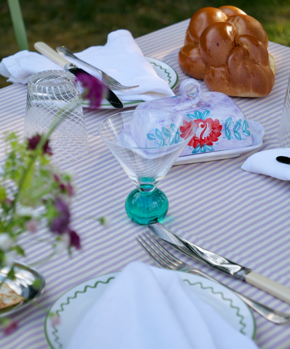 Outdoor table setting with a striped tablecloth, glassware, and bread.