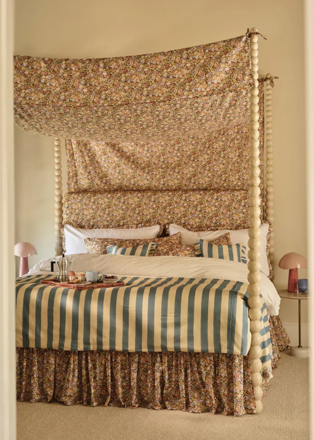 Bedroom with a canopy bed featuring striped bedding and decorative pillows.