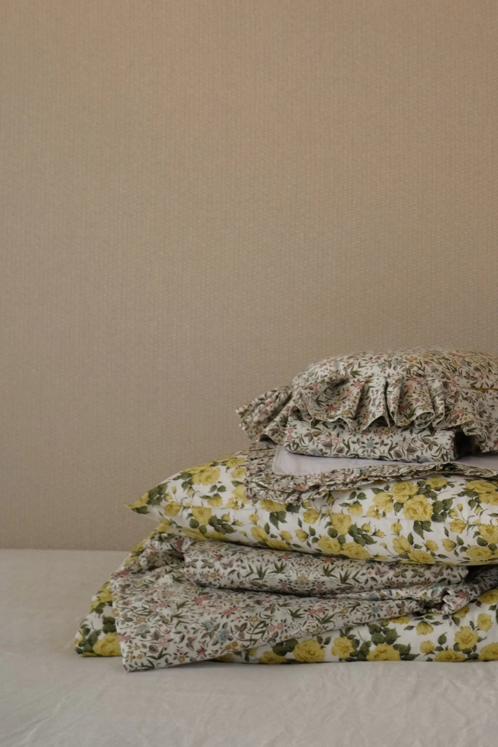 Stack of floral-patterned fabric pieces on a beige surface with a beige background