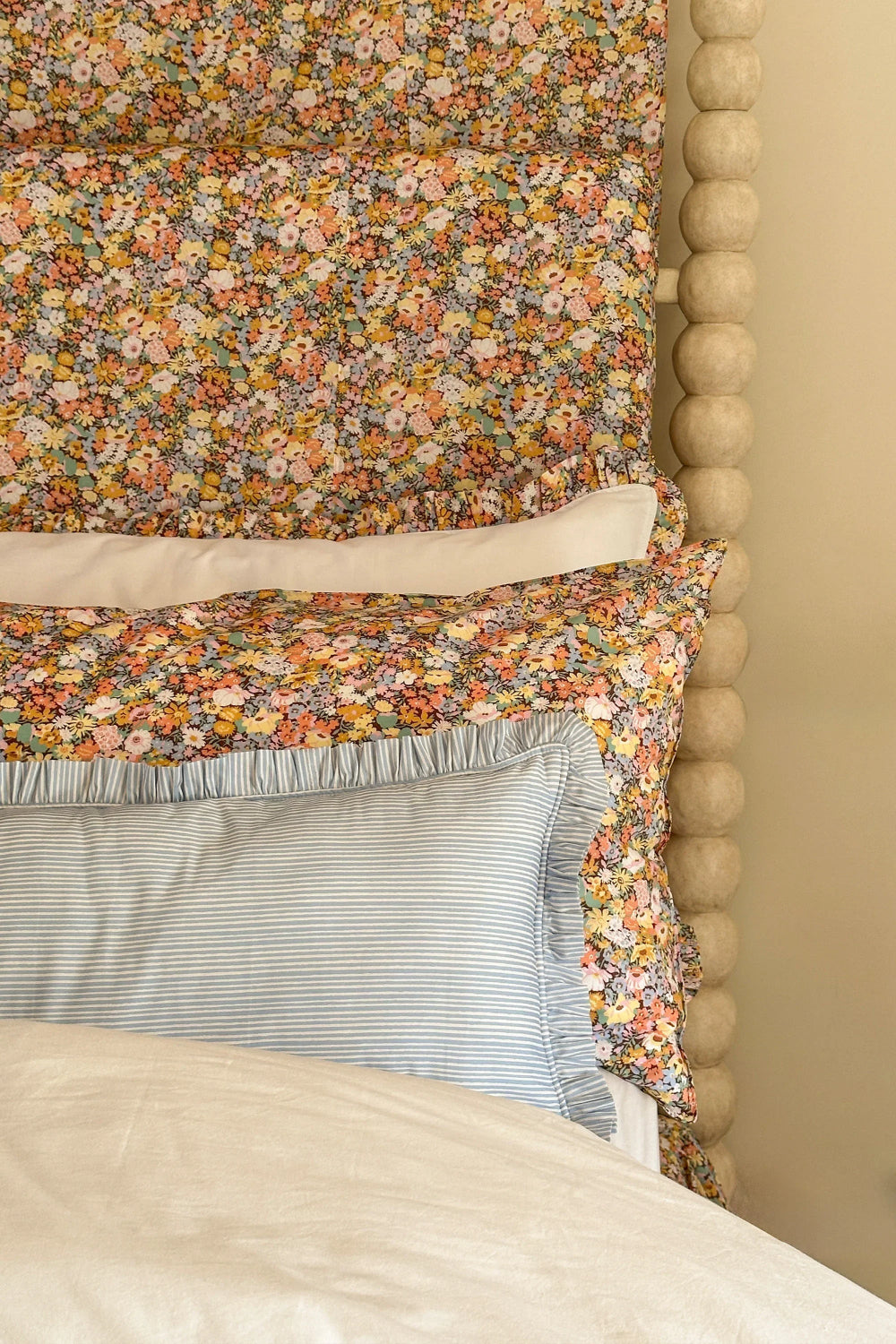 Floral patterned headboard with a textured wooden frame and striped pillow.