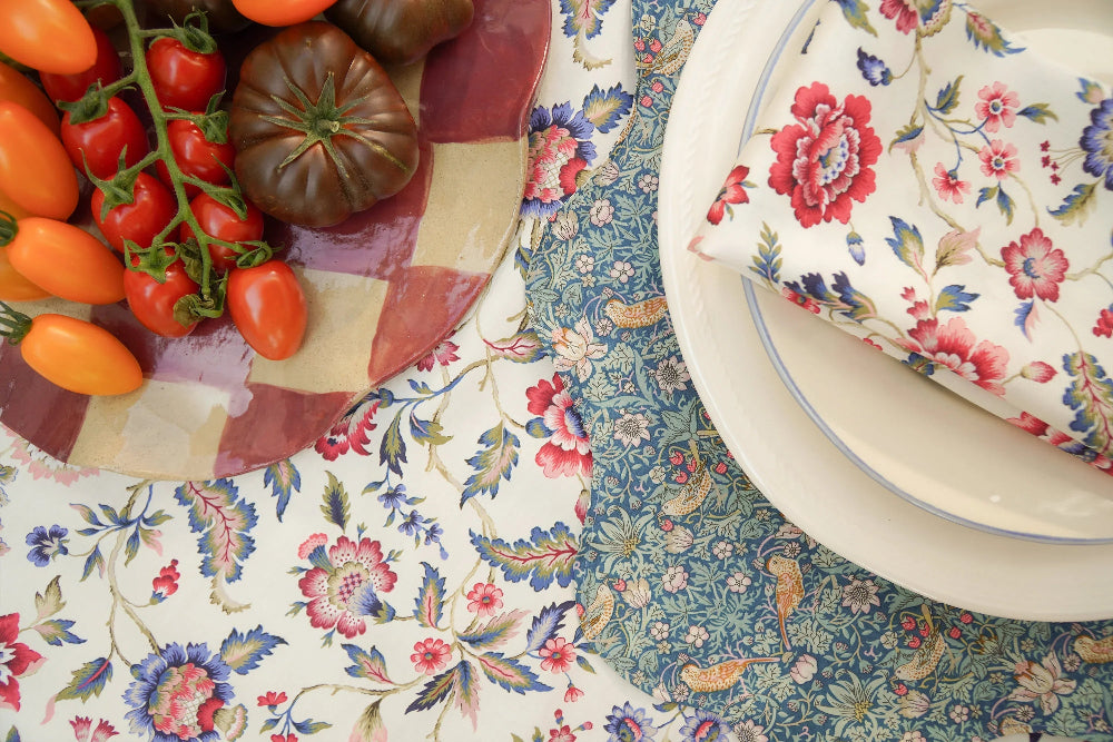 Floral tablecloth with a bowl of tomatoes and a floral-patterned box.