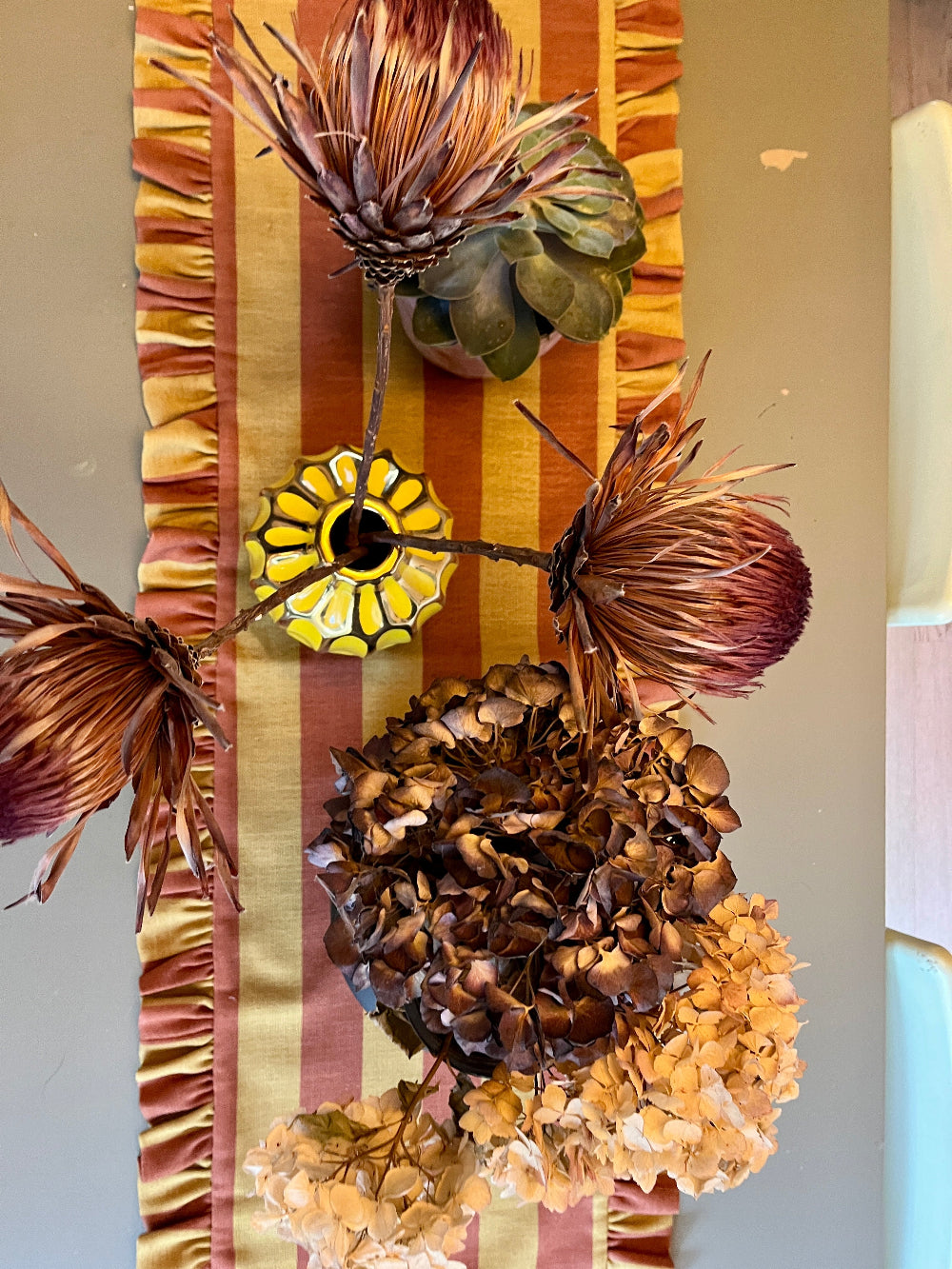 Colourful striped ruffled table runner styled with decorative objects for a dining table