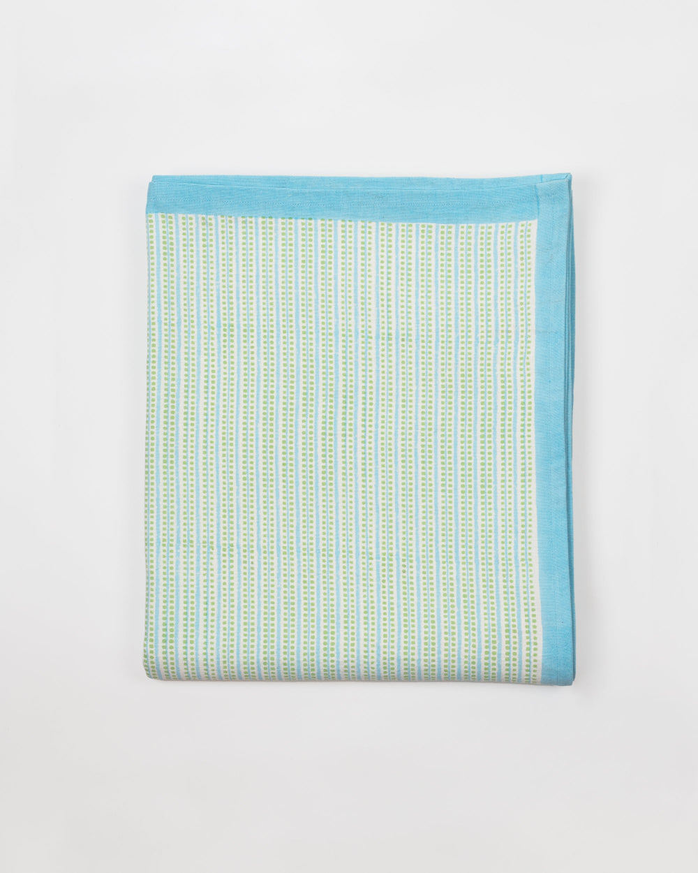 Green dash and dot tablecloth folded with blue border on a light grey background