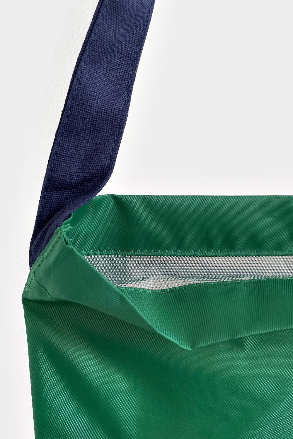 Close-up of a green bag with a visible zipper on a white background
