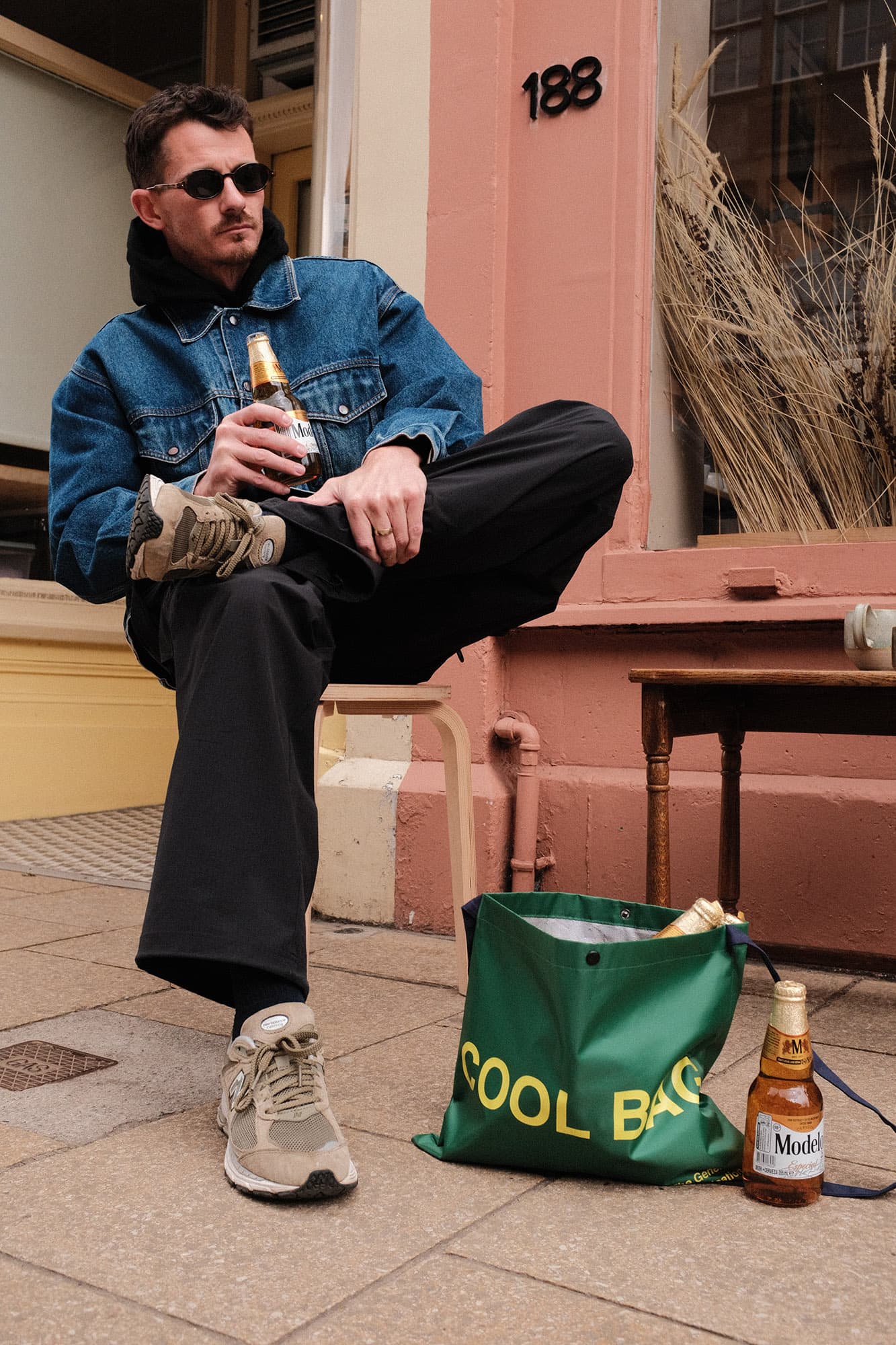 Man sitting on steps with a bottle and 'Cool Bag' in an urban setting