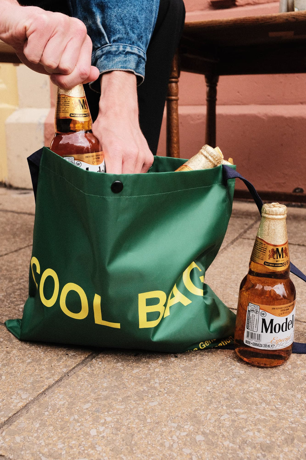 Green 'Cool Bag' with Model beer bottles on a stone surface