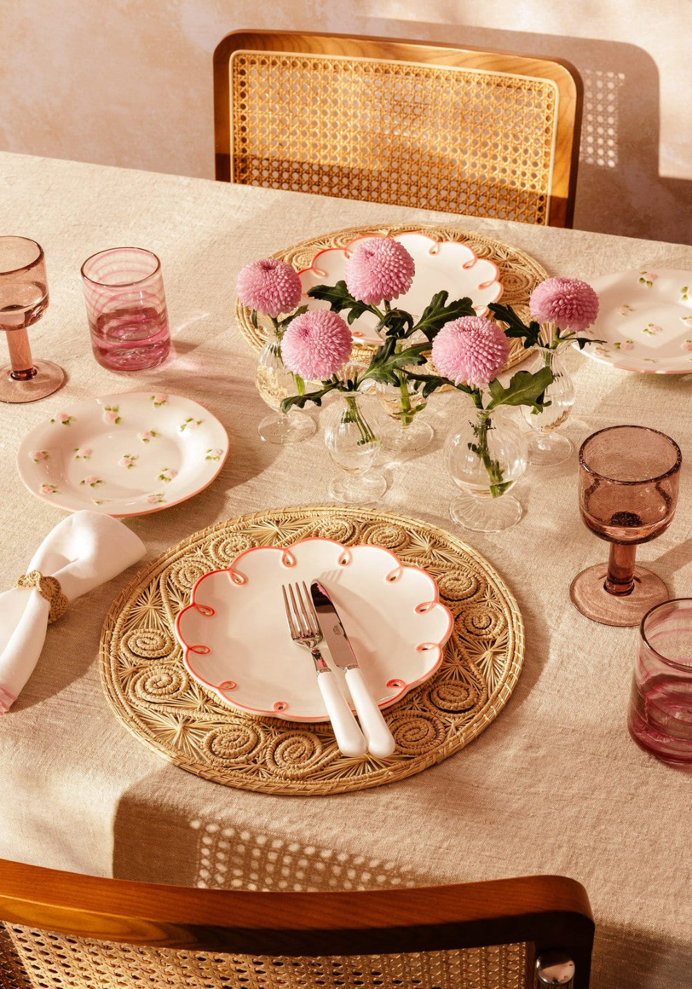 Dining table setting with decorative plates, glasses, and flowers.