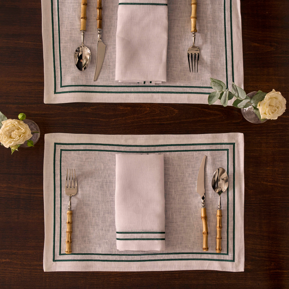Set of tableware on linen striped placemats with cutlery and napkins on a wooden surface.