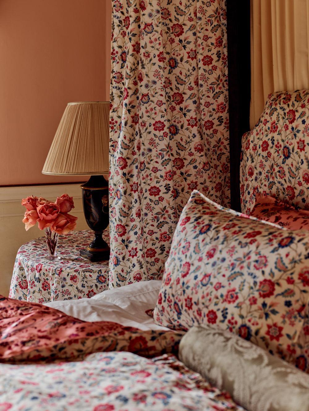 Bedroom with floral bedding, curtains, and lamp on a side table.