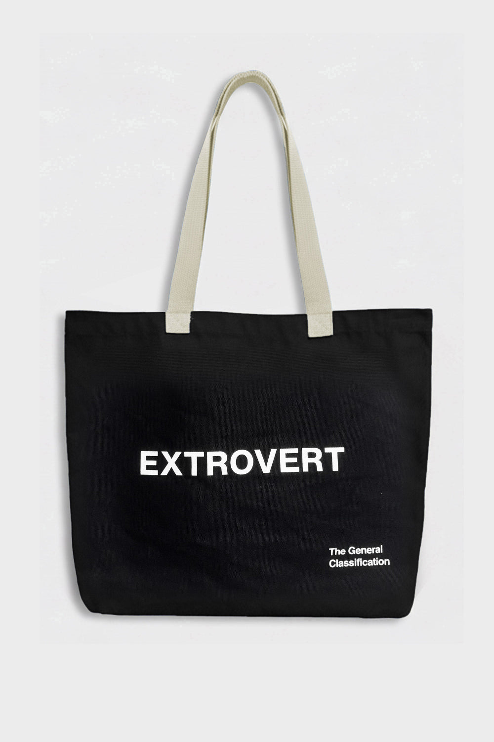 A black canvas tote bag with cream-colored shoulder straps and white printed text reading 'EXTROVERT' and 'The General Classification' on a light gray background.