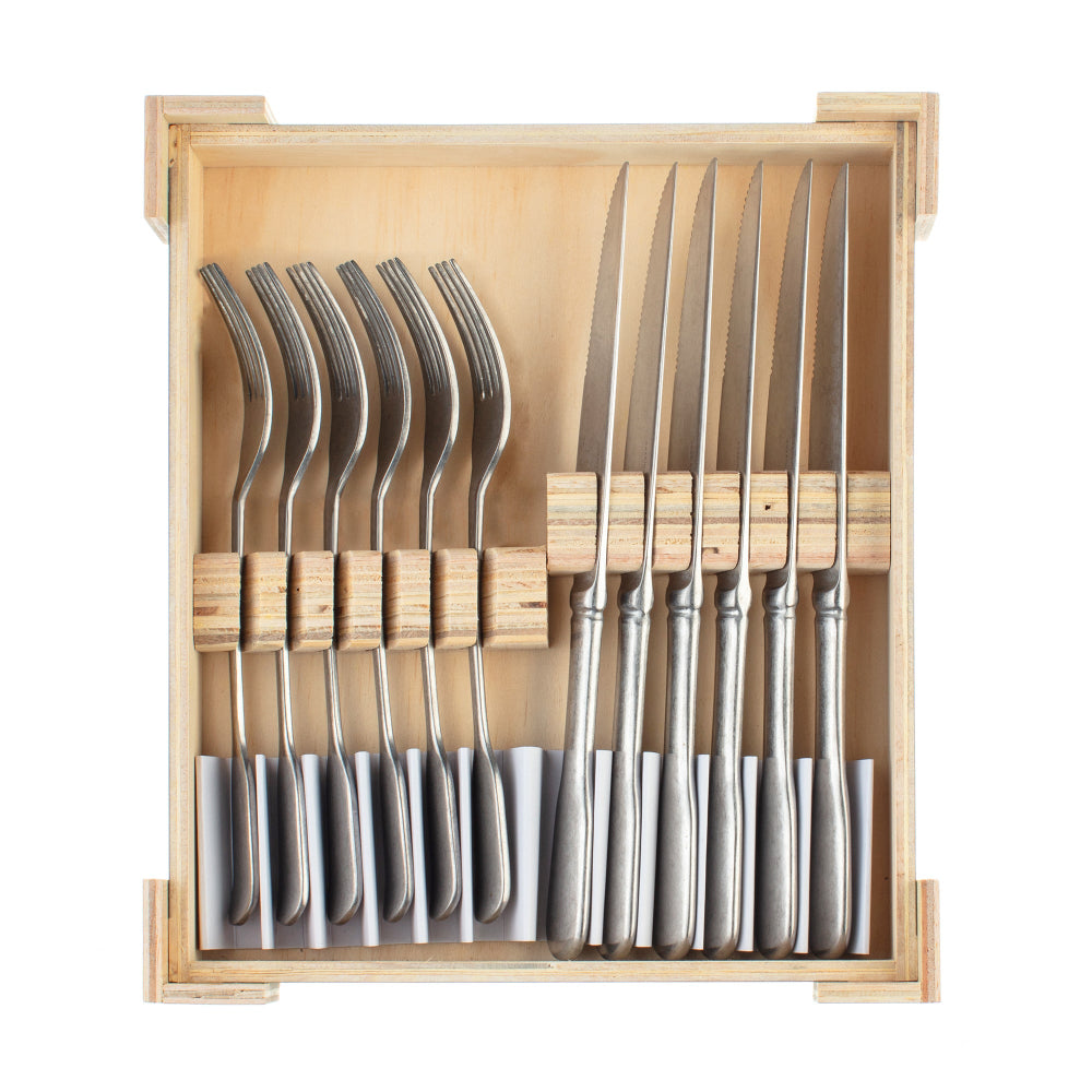Set of silver cutlery including knives and forks in a wooden box on a white background