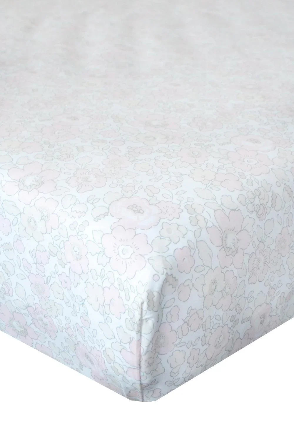 Floral patterned fitted sheet on a bed with a white background